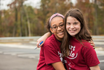 two Heart and Sole participants smile in maroon Heart and Sole shirts at a local practice